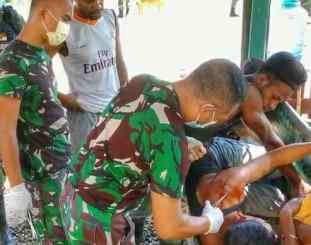 Anggota TNI saat membantu warga yang terluka akibat sabetan senjata tajam 